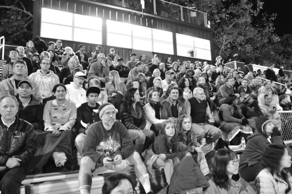 Parents and other fans sit on the bleachers to cheer on the competing players during the Paly Homecoming football game.