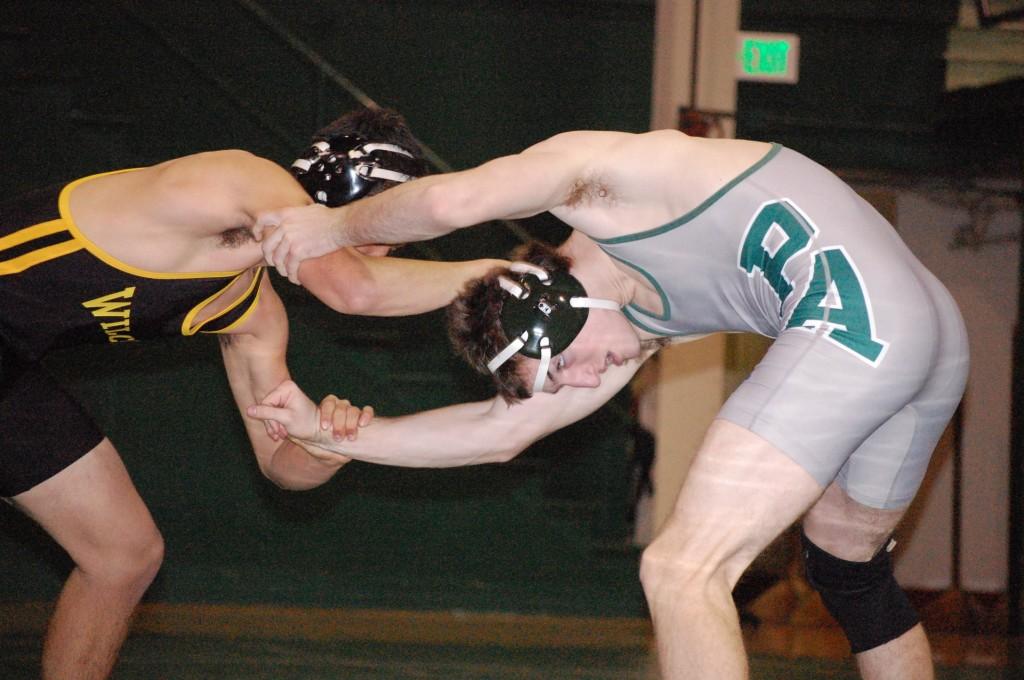 Kevin Schumacher (15) grabs one shoulder of his opponent in attempt to throw him to the floor. Schumacher lost his match and Wilcox earned three more points. 